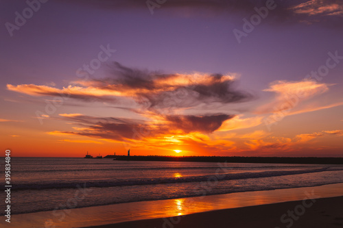 sunset on the beach in the Atlantic ocean Viana do Castelo Praia do Cabedelo Cabedelo beach colorful clouds with a lighthouse © Nauris