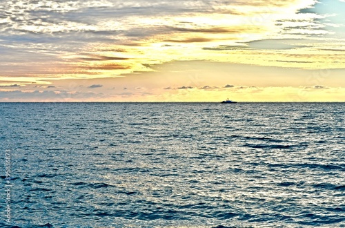 Seascape with gray sea  cloudy sky and ship on the horizon during sunset