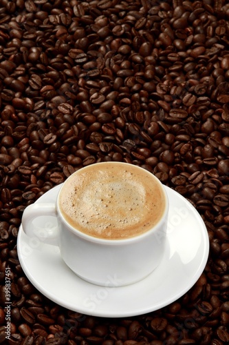 Cup of coffee surrounded by coffee beans