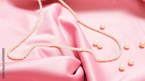 pearl beads on pink luxury satin fabric. Background. elegant wallpaper