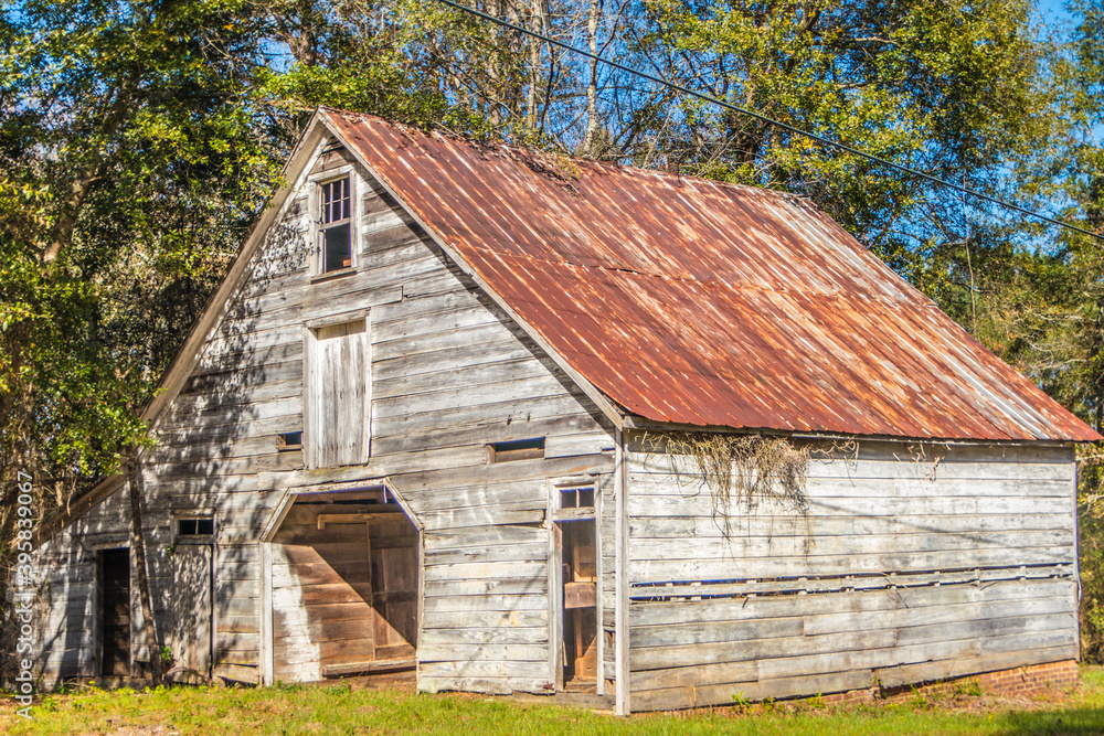 An old abandoned structure in the rural south of Georgia with trees grass