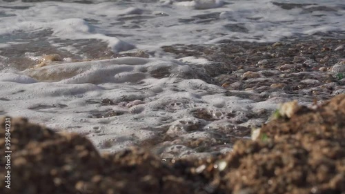 Pebble stones close up in front of sea waves.