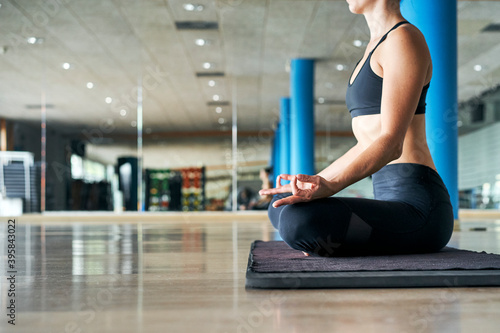 Unrecognizable woman practicing yoga in a gym, exercising in black sportswear, doing meditation exercises. photo