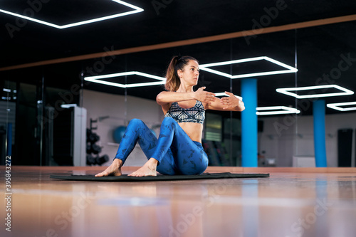 Attractive young woman practicing yoga or pilates in a gym  exercising in blue sportswear  doing stretching exercises. Full length silhouette.