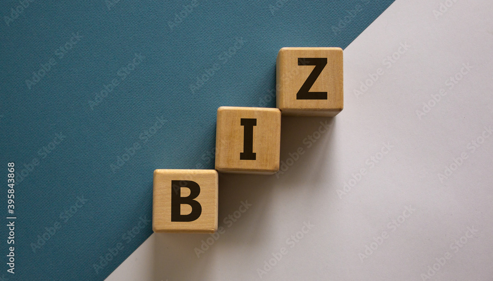 Business concept success process. Wooden block with a word 'biz' stacking as step stair on paper blue and white background, copy space. Biz concept. Business concept success process. Wooden block with a word 'biz' stacking as step stair on paper blue and white background, copy space. Biz concept.