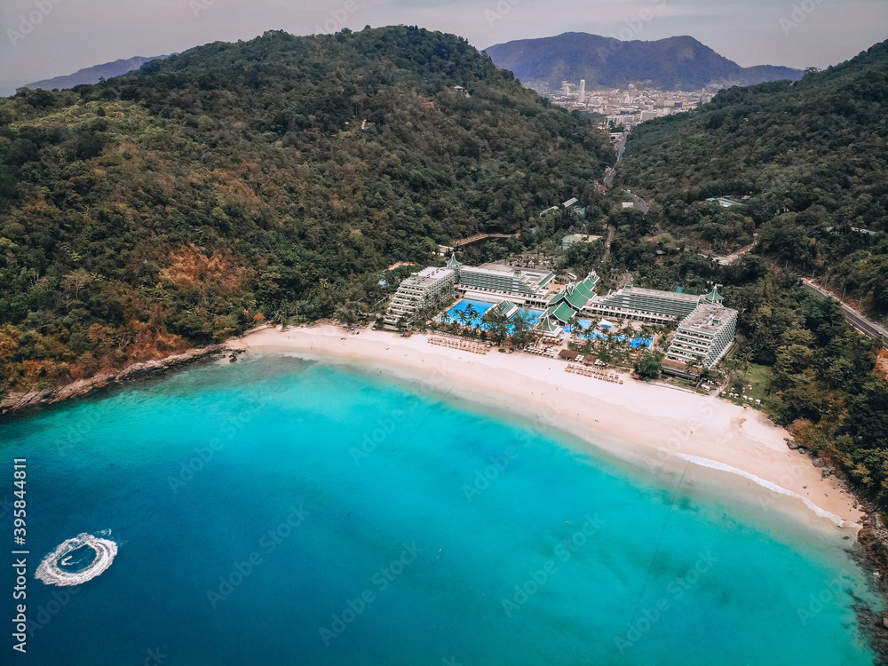 Aerial view of the idyllic bay with sandy beach and luxurious hotel between the treed hills; paradise concept.