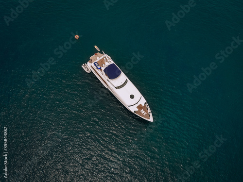 Drone shot of the beautiful white yacht in the warm blue sea; millionaire concept.