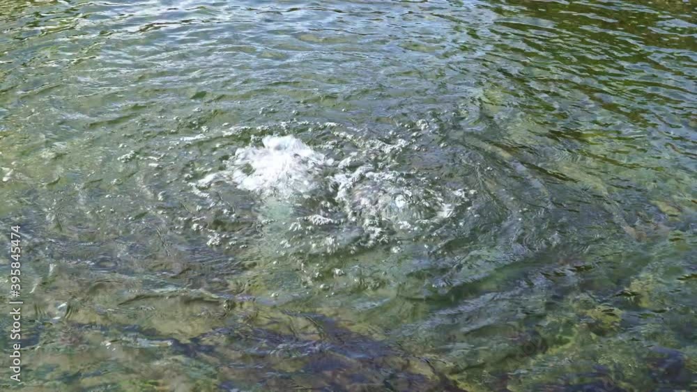 water enters an artificial pond with clean water and a rocky bottom