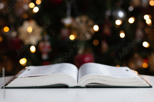 Bible open in front of Christmas tree