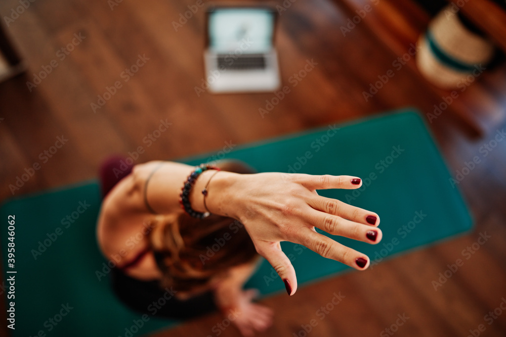 A middle-aged woman doing yoga, following an online tutorial on laptop during corona virus pandemic. A middle-aged woman doing yoga, following an online tutorial on laptop during corona virus pandemic.