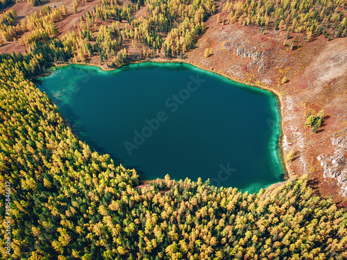Aerial view of a huge lake with brilliant turquoise water which is located right in the middle of a dense saturated forest