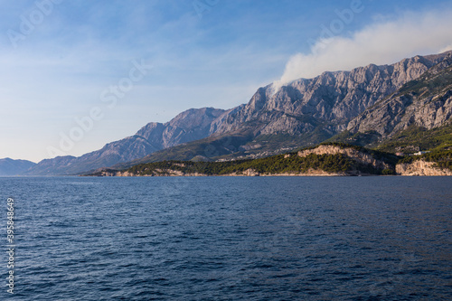Blick vom Meer auf die Küste in Kroatien. Berge mit Rauchwolken am Himmel