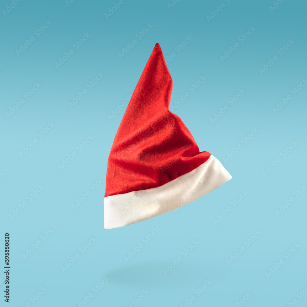 Santa Claus hat levitation on blue background. Minimal Christmas concept. Flying cap in the air