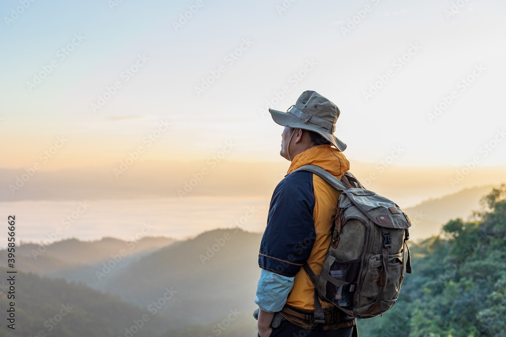 Hipster male hiker with backpack enjoying sunset on peak of foggy mountain. Tourist traveler on background view mockup. Hipster male hiker with backpack enjoying sunset on peak of foggy mountain. Tourist traveler on background view mockup.