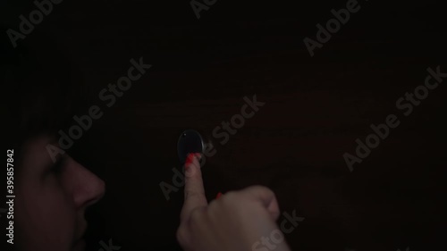 worried woman looking through the peephole in theevening, eye close-up photo