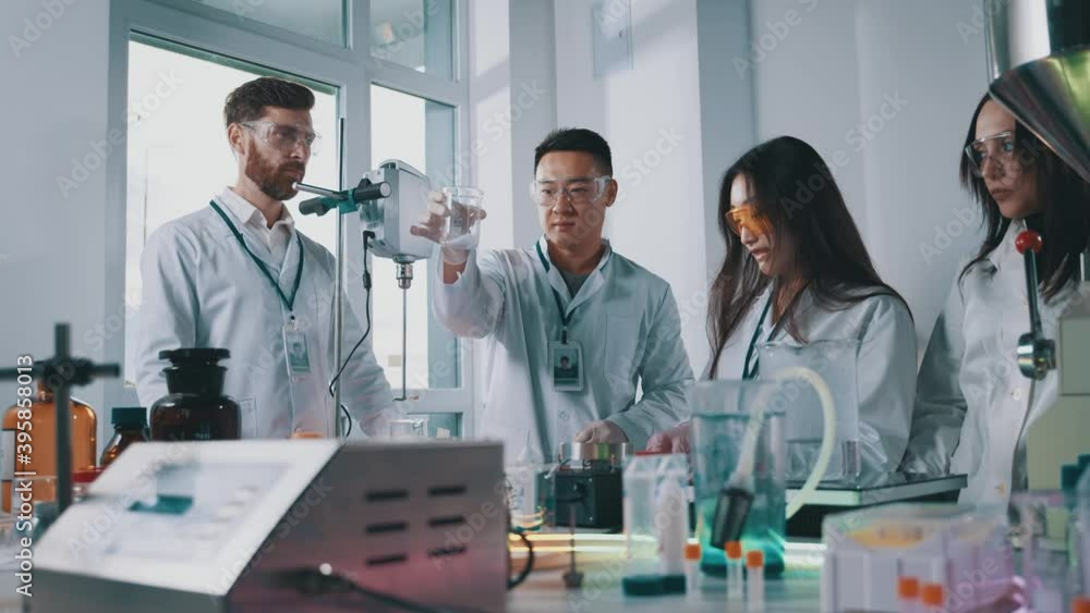 Professional team of scientists perform research in medical laboratory mixing chemical liquids using lab tools cooperating. Multi-race people. Pharmacy concept. Professional team of scientists perform research in medical laboratory mixing chemical liquids using lab tools cooperating. Multi-race people. Pharmacy concept.