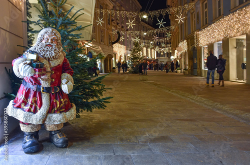 Graz, Austria - November 30, 2019: Santa Claus and beautiful Christmas decorations at night in the city center. Shopping rush during holidays concept, long exposure used for movement effect.