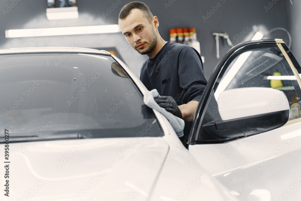 Man in a garage. Worker polish a car. Man in a black uniform. Man in a garage. Worker polish a car. Man in a black uniform.