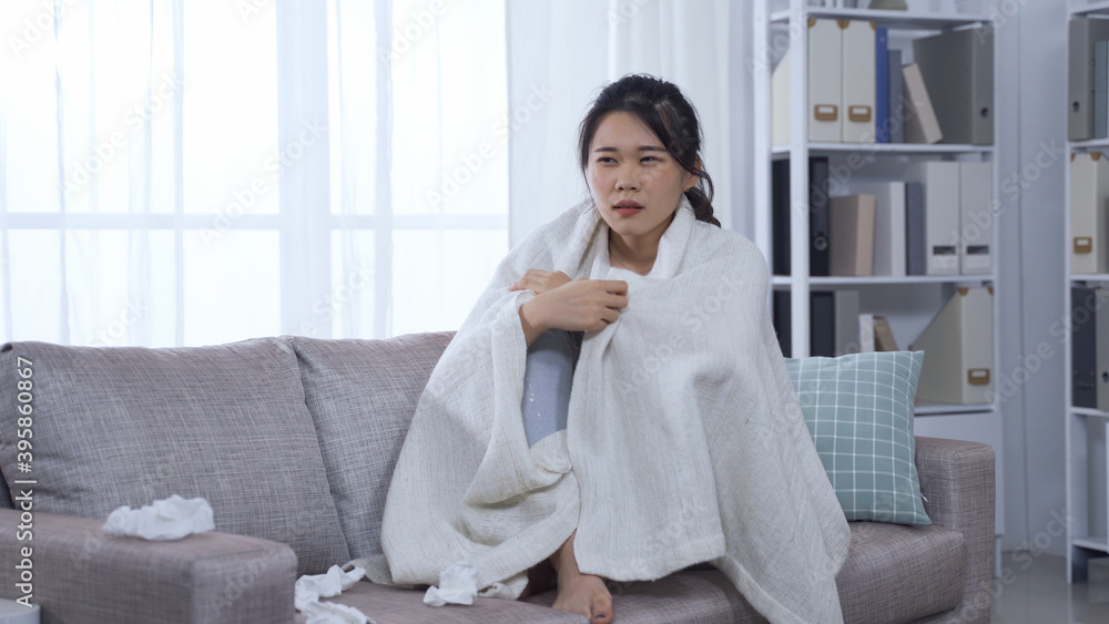 sickness asian female patient covered in blanket staying at home with coronavirus and holding tissue. sickness asian female patient covered in blanket staying at home with coronavirus and holding tissue.