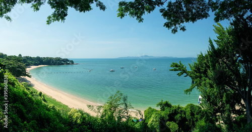 Panorama image of Tropical beautiful seascape view of green trees with blue sea in background at Chonburi, Thailand. © Angkana