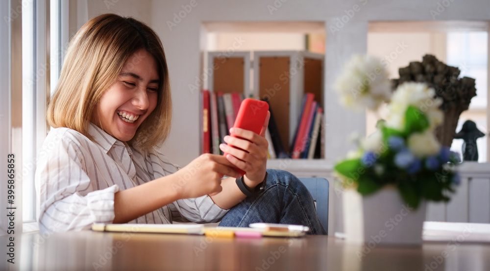 Smiling young woman using smart phone browsing and messaging with friends at her workspace. Smiling young woman using smart phone browsing and messaging with friends at her workspace.