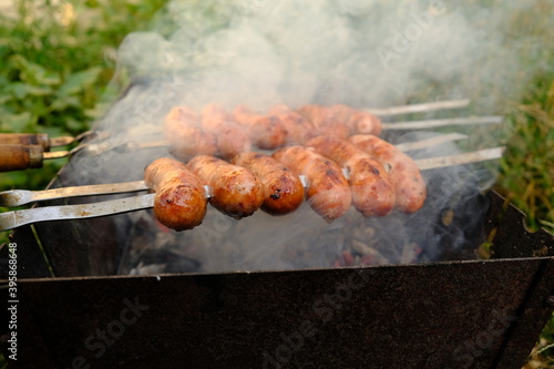 juicy meat sausages are cooked on a fire in smoke, outdoor cooking