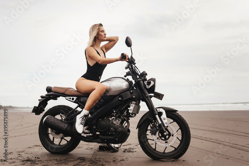 Beautiful woman having fun driving her motorcycle, enjoying the sunset on the beach