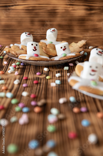 Pl  tzchen mit Marshmallows  Zuckerguss und Schokolinsen die aussehen wie geschmolzene Schneem  nner auf Tellern zur Weihnachtszeit