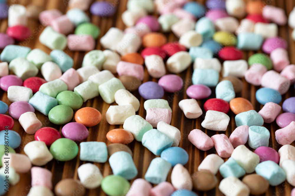 Schokolinsen und kleine Marshmallows auf einem Tisch aus Holz vertreut Schokolinsen und kleine Marshmallows auf einem Tisch aus Holz vertreut