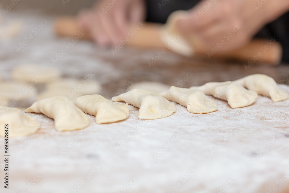 Woman rolls the dough with a rolling pin on the table. Woman rolls the dough with a rolling pin on the table.