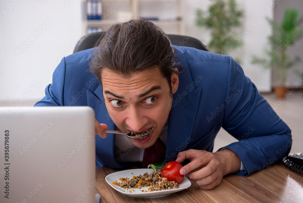 Hungry male employee eating buckwheat during break Hungry male employee eating buckwheat during break