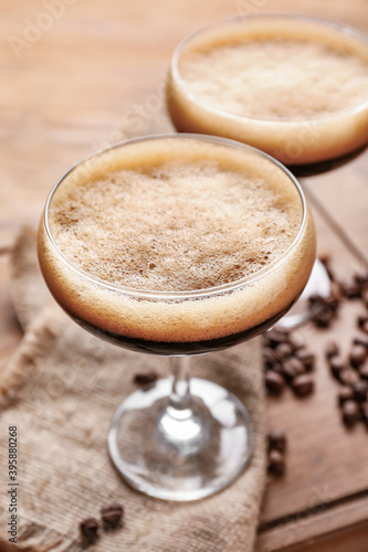 Two glasses of tasty espresso martini cocktail on wooden board