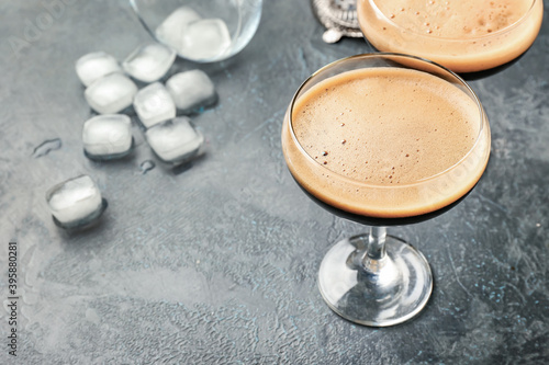 Two glasses of tasty espresso martini cocktail and ice cubes on table