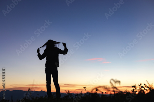 Silhouette of young girl standing lonely on mountain at beautiful sunset © AungMyo