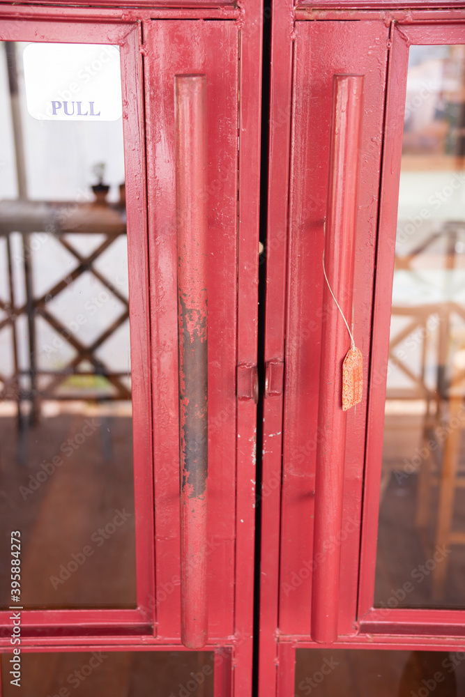 Glass door with old red wood frame, vintage style. The paint on the door handle was scratched to see the rusted iron.