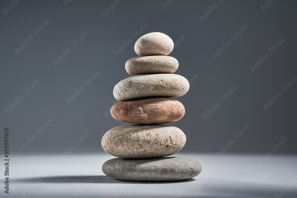 Balancing pyramid of sea pebbles on a gray background, the concept of harmony and balance, heavy and light. Stones in the form of scales with balancing stones. Balancing pyramid of sea pebbles on a gray background, the concept of harmony and balance, heavy and light. Stones in the form of scales with balancing stones.