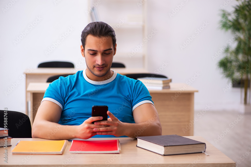 Exhausted male student preparing for the exams in the classroom Exhausted male student preparing for the exams in the classroom