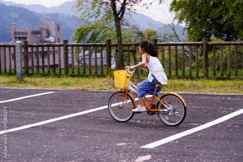 Fototapeta Naklejka Na Ścianę i Meble -  桜並木で自転車に乗る女の子