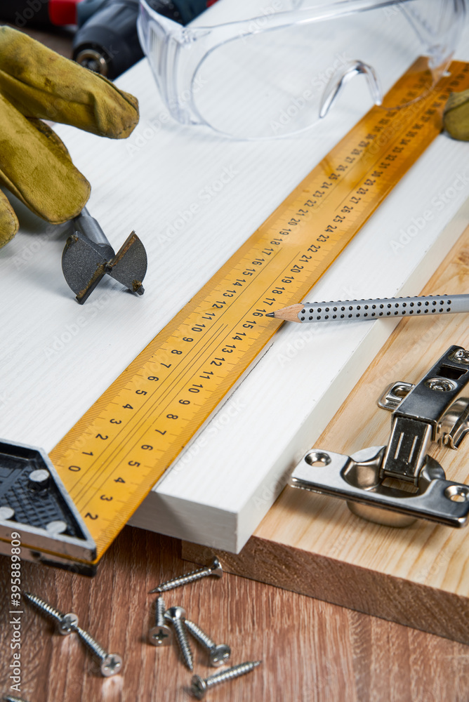 Installation of furniture hinges in the chipboard, tools and accessories needed to perform the work. Small carpentry work at home, the concept of a home master, self-repair of the house Installation of furniture hinges in the chipboard, tools and accessories needed to perform the work. Small carpentry work at home, the concept of a home master, self-repair of the house