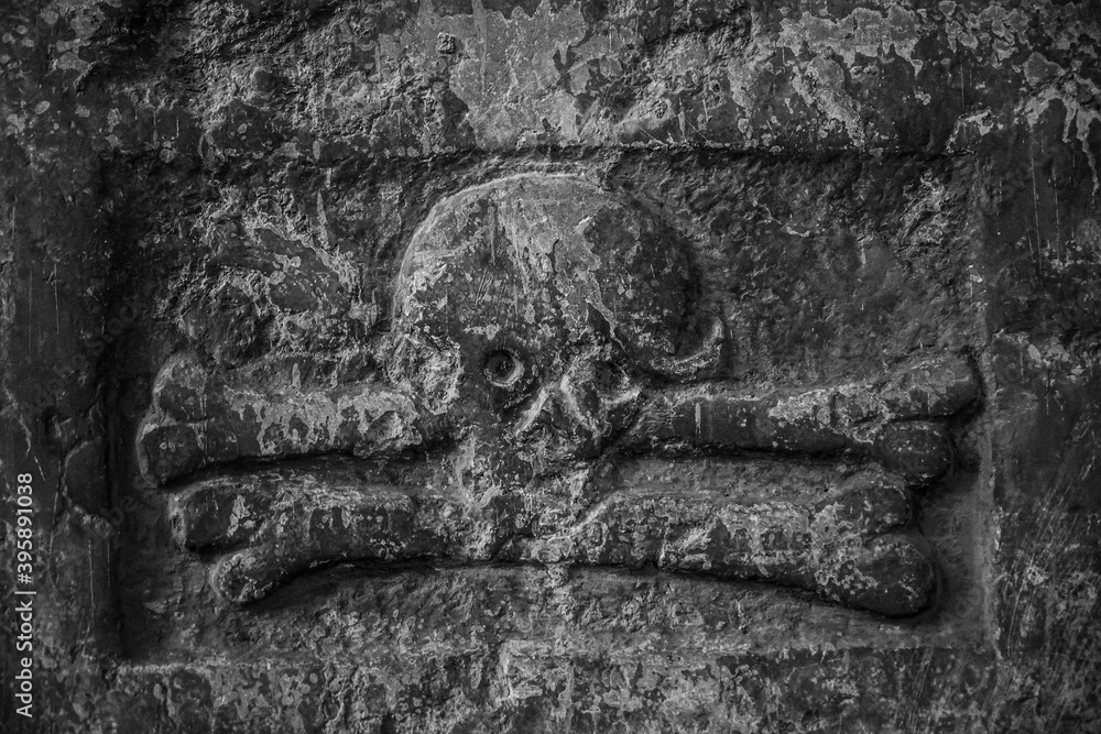 Ancient destroted terrible sculpture of a skull and crossed bones