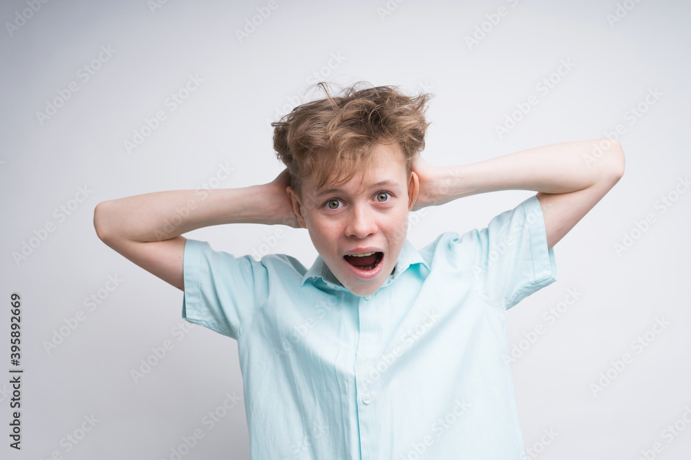A Caucasian boy is screaming with his ears closed by his hands A Caucasian boy is screaming with his ears closed by his hands