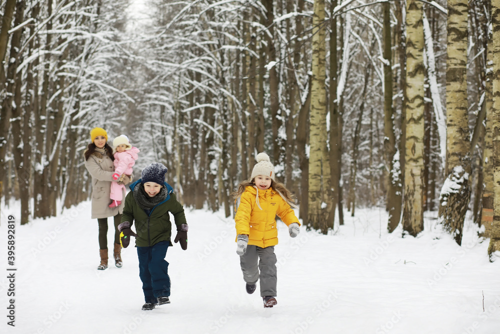 Happy family playing and laughing in winter outdoors in the snow. City park winter day.