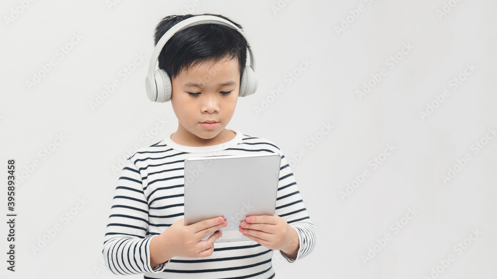technology - a lovely young pupil standing with his tablet wearing headphones technology - a lovely young pupil standing with his tablet wearing headphones