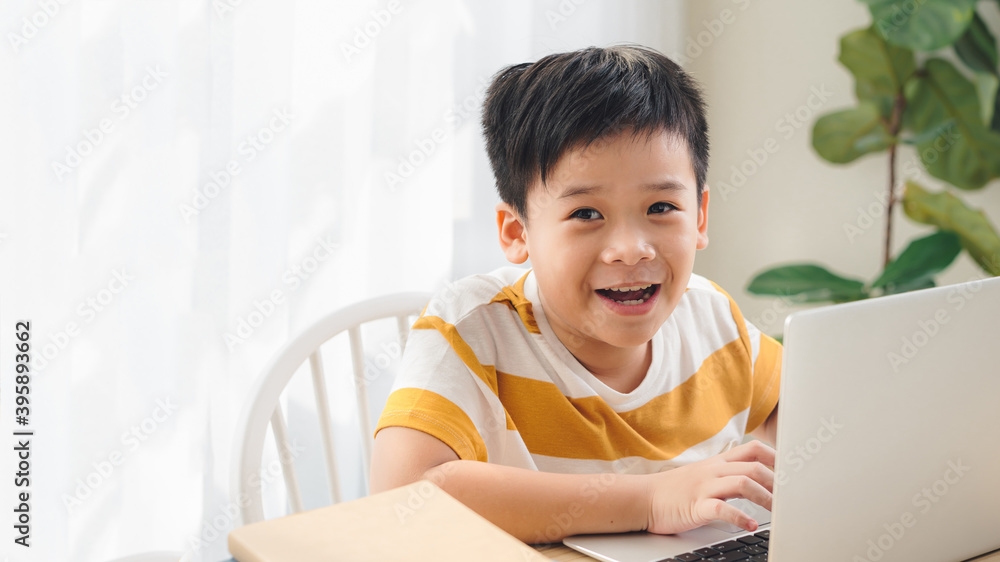 happy cute little school boy doing homework and using laptop at home happy cute little school boy doing homework and using laptop at home