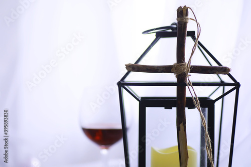 Religious concept. Handmade wooden cross on a white background. Wine glass lamp with candles. © alexkich