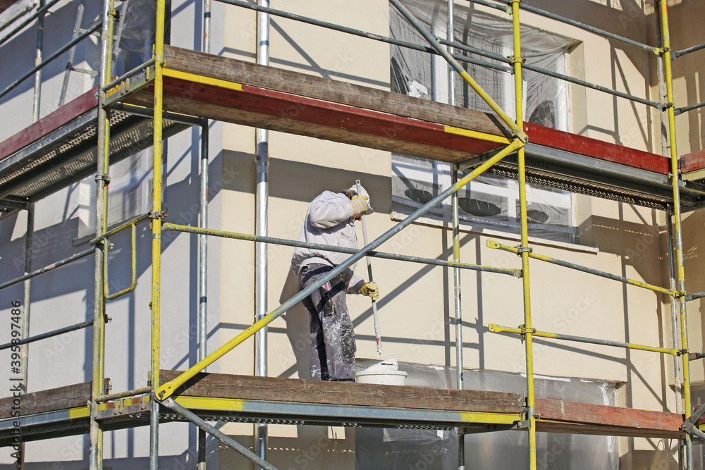 Maler beim Fassadenanstrich eines neuen Wohnhauses