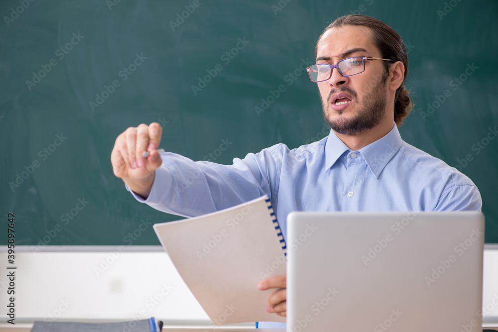 Young male teacher in the classroom in tele-education concept Young male teacher in the classroom in tele-education concept