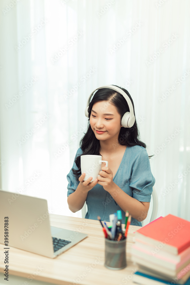 Smart asian girl desk work remote laptop watch seminar drink beverage mug in house indoors Smart asian girl desk work remote laptop watch seminar drink beverage mug in house indoors