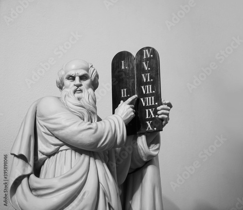 jewish Jehovah Statue of God with a book in their hands against on a white background. Biblical Ten Commandments inscribed on stone tablets photo
