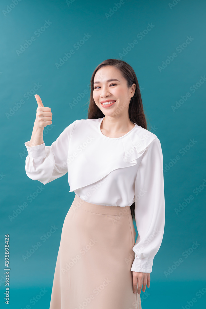 Smiling pretty young woman showing thumb up isolated on the blue background Smiling pretty young woman showing thumb up isolated on the blue background